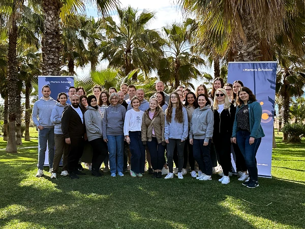 Gruppenfoto des Teams von Mertens Schabow vor Palmen am Meer