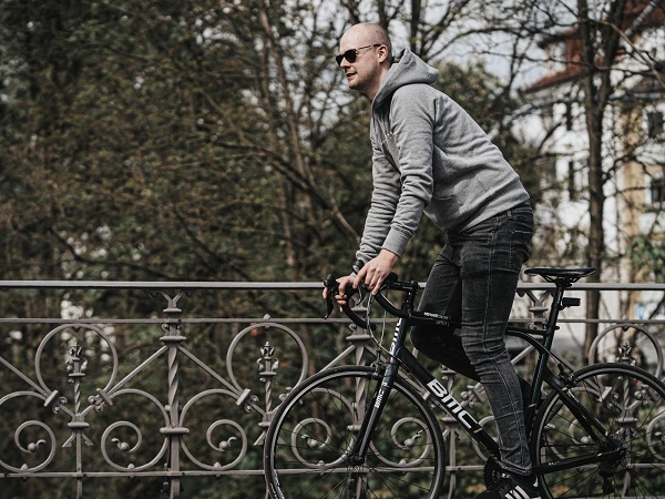 Mann auf Fahrrad auf einer Brücke mit Bäumen im Hintergrund