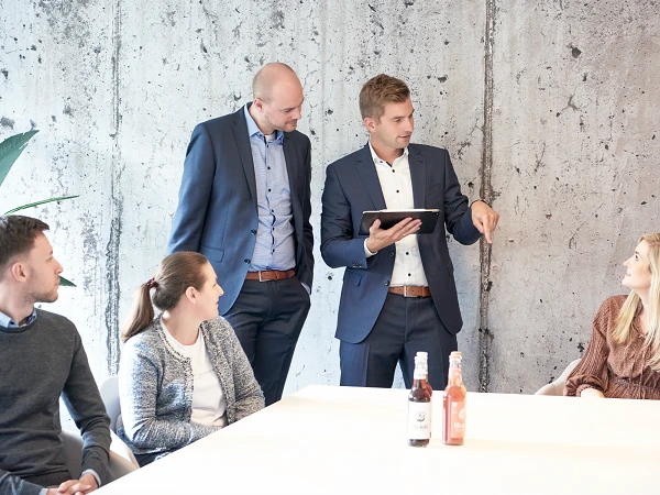 Fünf Leute in einem Besprechungsraum am reden mit Getränken auf dem Tisch