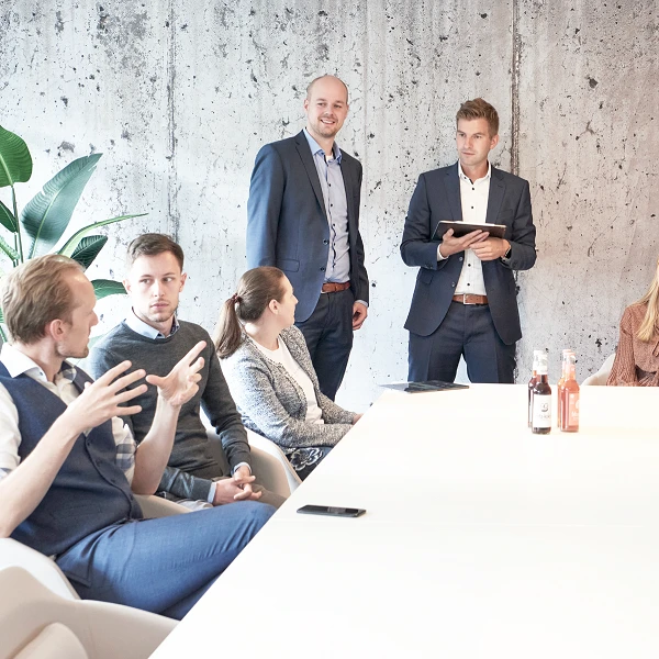 Mehrere Leute in Besprechungsraum an einem großen Tisch sitzend und redend