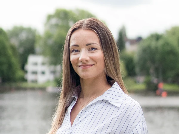 Frau mit langen braunen Haaren im gestreiften Hemd vor Flusslandschaft