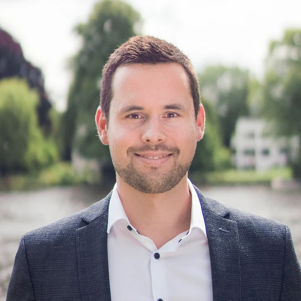 Mann im dunklen Sakko vor Flusslandschaft