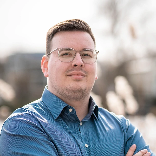 Mann mit Brille und blauem Hemd, verschränkt die Arme vor See