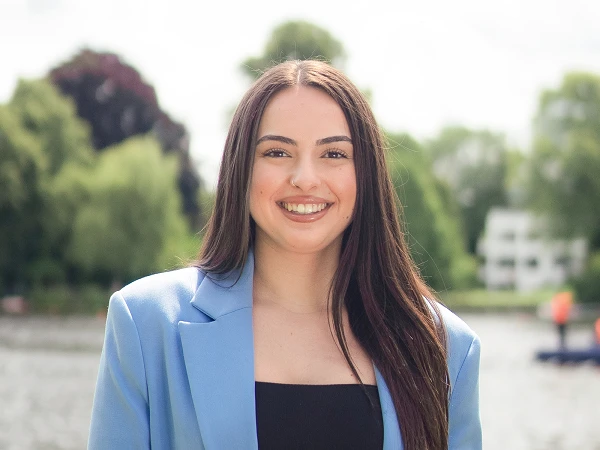 Frau mit glattem Haar in blauem Blazer am Flussufer