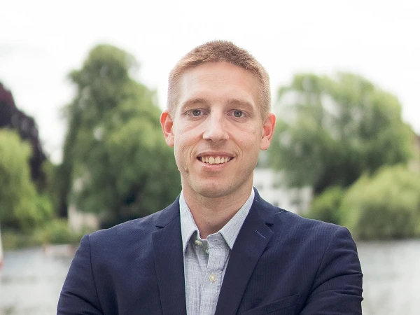 Mann in blauem Sakko vor Wasser